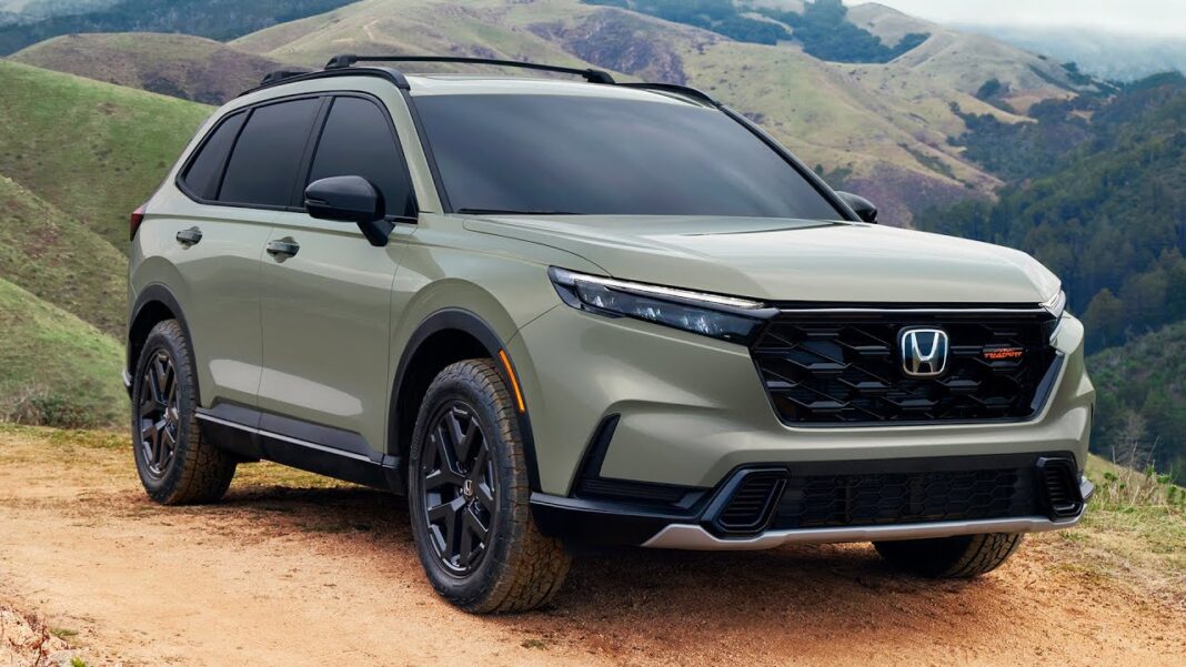 2026 Honda CR-V Hybrid TrailSport parked on a forest trail showcasing rugged design and Ash Green Metallic paint